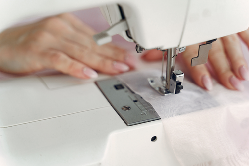 close-up of hands on fabric using a sewing machine