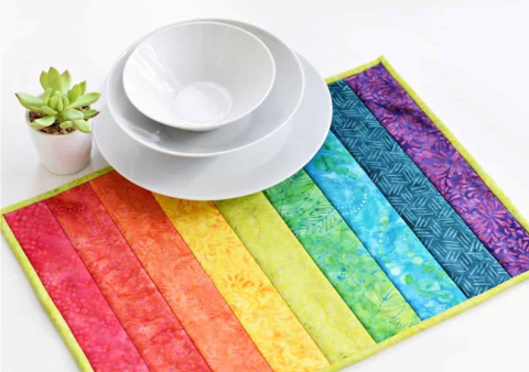 Rainbow-colored placemat with a dish and plant.
